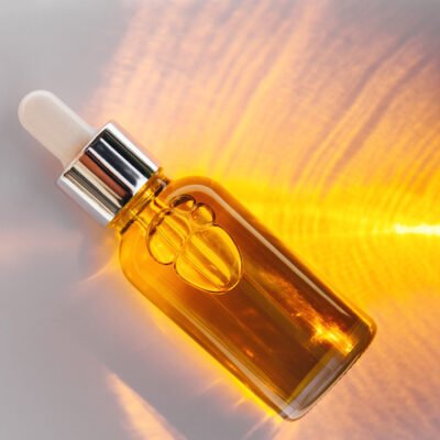 Dropper glass Bottle light and shadow Mockup of glass dropper bottle with a metal cap and yellow essential oil on a background with an abstract fire pattern of light and shadow. Eco cream, serum, cosmetics, massage oil. Copy space
