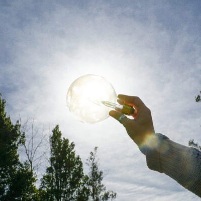 Grasping Innovation: A person holding a light bulb against the daylight sky, symbolizing creativity and sustainable ideas. Solar energies Grasping Innovation: A person holding a light bulb against the daylight sky, symbolizing creativity and sustainable ideas. Solar energies